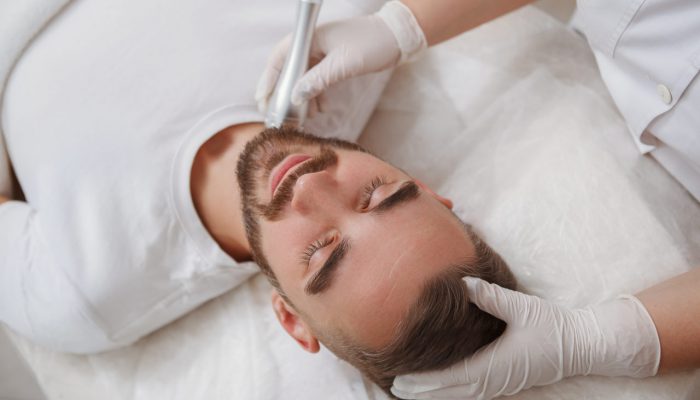 unrecognizable-cosmetologist-using-rflifting-skincare-apparatus-neck-male-client_Easy-Resize.com